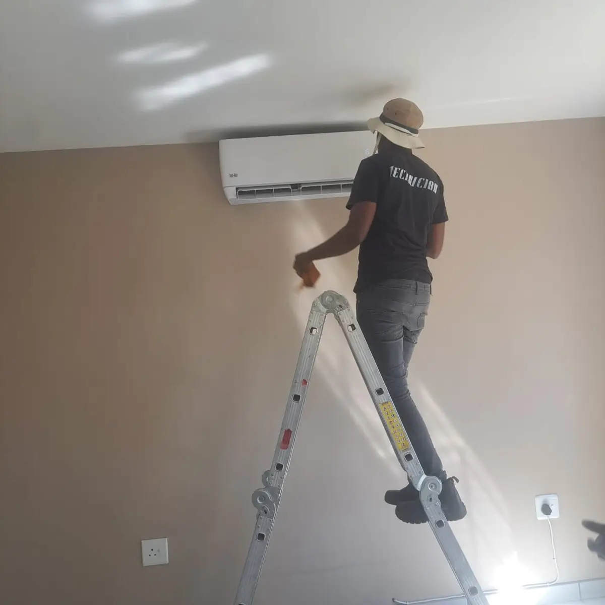 Technician servicing a split aircon unit